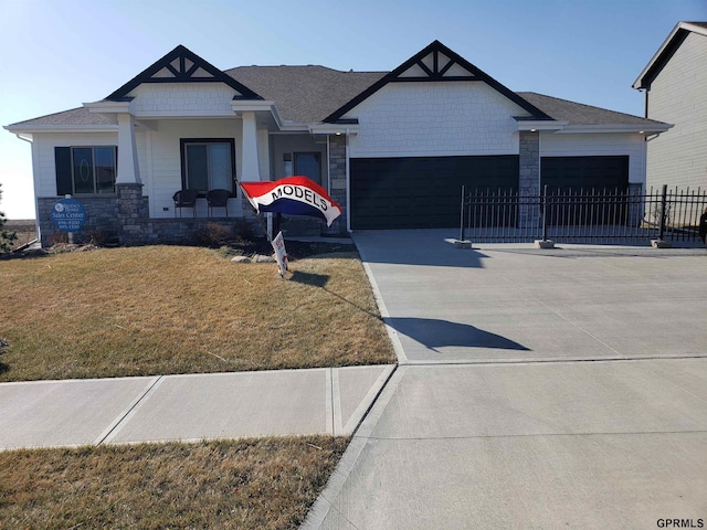 view of front of property with a porch, a garage, and a front lawn