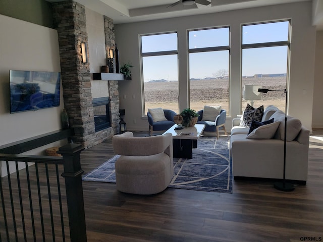 living room with a stone fireplace, ceiling fan, and dark hardwood / wood-style flooring