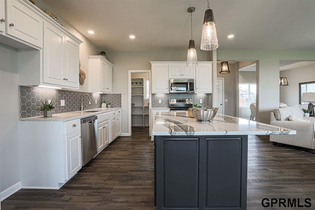 kitchen featuring pendant lighting, stainless steel appliances, a kitchen island, white cabinets, and sink