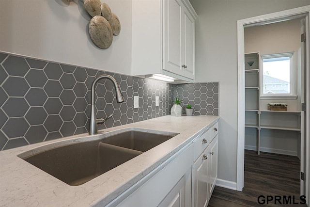 kitchen featuring sink, light stone countertops, decorative backsplash, and white cabinetry