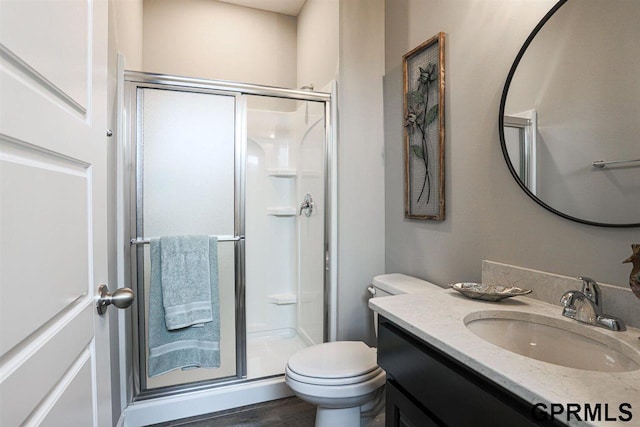 bathroom featuring wood-type flooring, an enclosed shower, vanity, and toilet