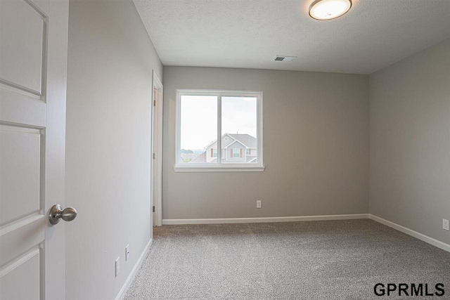 empty room with a textured ceiling and light carpet