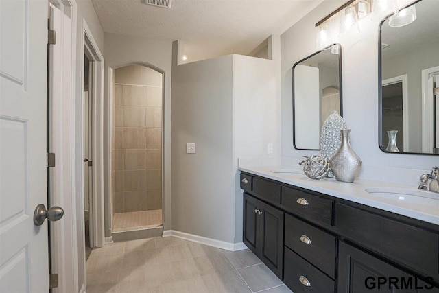 bathroom featuring vanity, tiled shower, and a textured ceiling