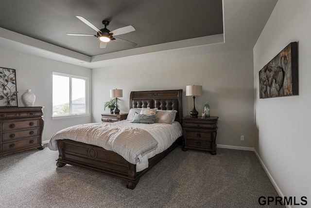 carpeted bedroom with a raised ceiling and ceiling fan