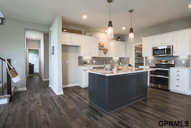 kitchen featuring stainless steel appliances, a center island with sink, white cabinetry, and light stone counters