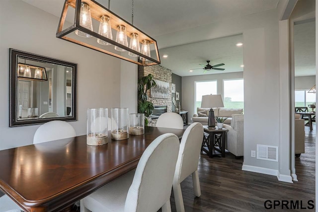 dining area with a fireplace, ceiling fan, and dark hardwood / wood-style floors