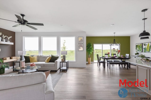 living room with ceiling fan with notable chandelier and wood-type flooring