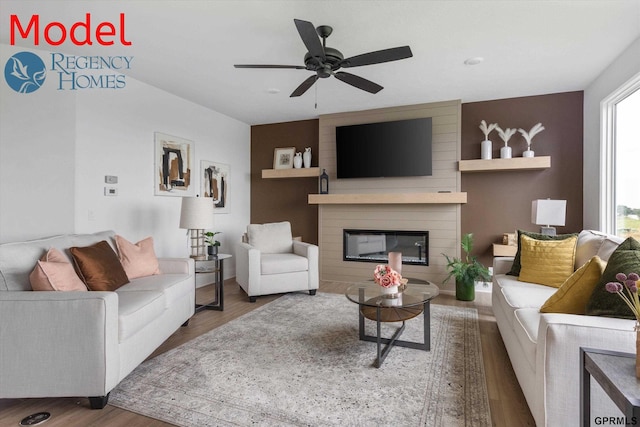 living room featuring a large fireplace, ceiling fan, and hardwood / wood-style floors