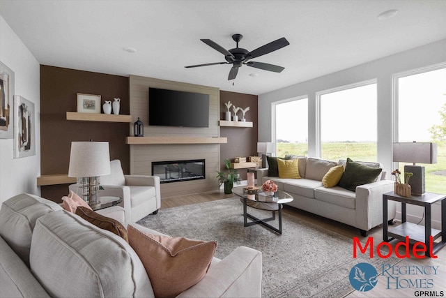 living room featuring a large fireplace, ceiling fan, and light hardwood / wood-style flooring