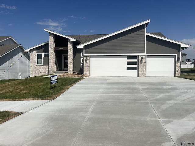 view of front facade with a garage, stone siding, and concrete driveway