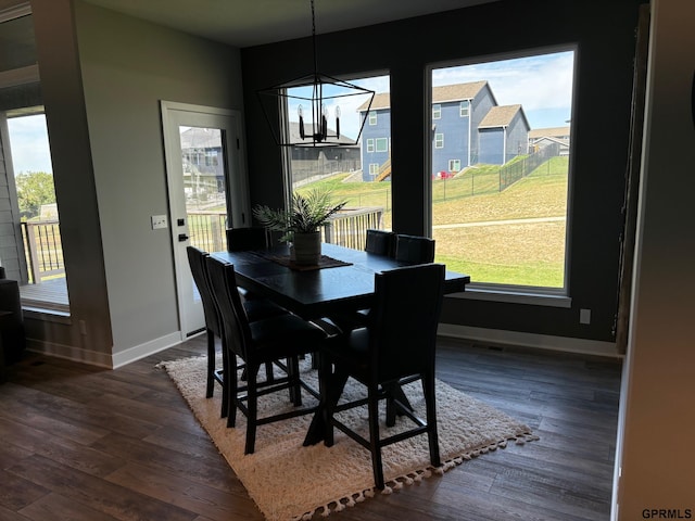 dining room featuring a chandelier, dark wood finished floors, and baseboards