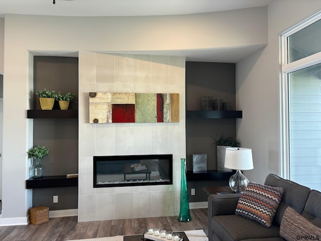 living room featuring wood finished floors, a tile fireplace, and baseboards