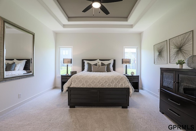 bedroom with light carpet, multiple windows, and a raised ceiling