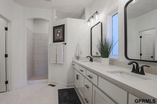 full bath featuring a walk in shower, marble finish floor, double vanity, and a sink