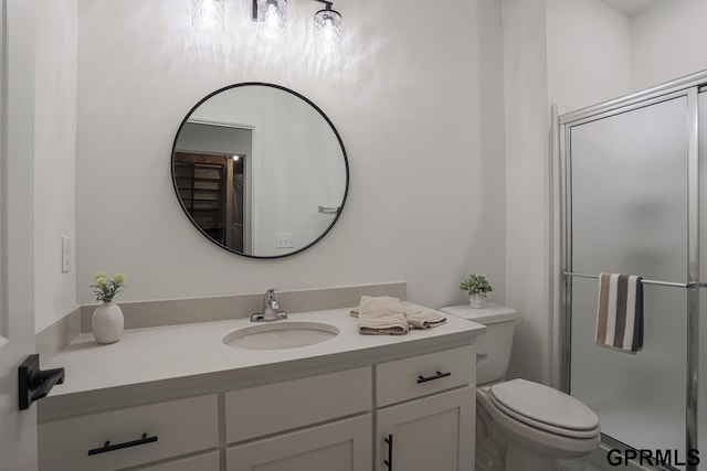 bathroom with toilet, a shower stall, and vanity