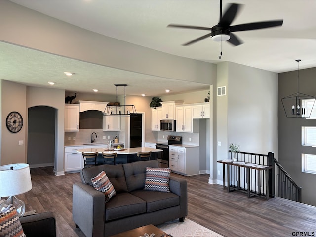 living room with baseboards, visible vents, dark wood finished floors, and arched walkways