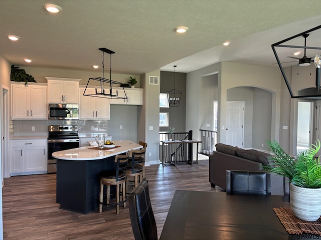 kitchen with tasteful backsplash, visible vents, appliances with stainless steel finishes, dark wood-type flooring, and white cabinetry