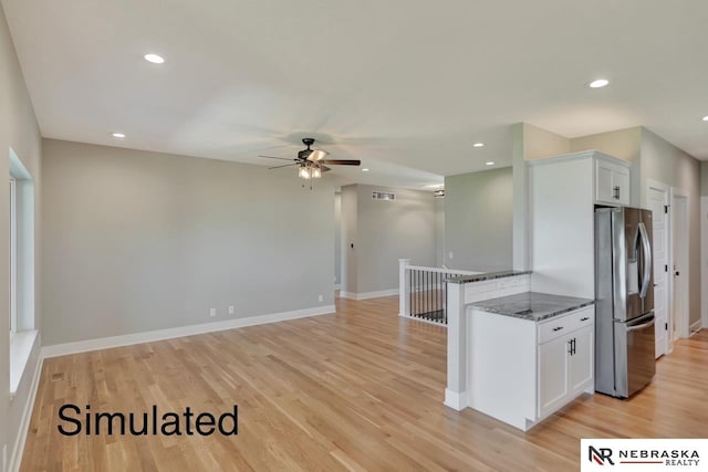 kitchen featuring visible vents, light wood-style flooring, freestanding refrigerator, and white cabinetry