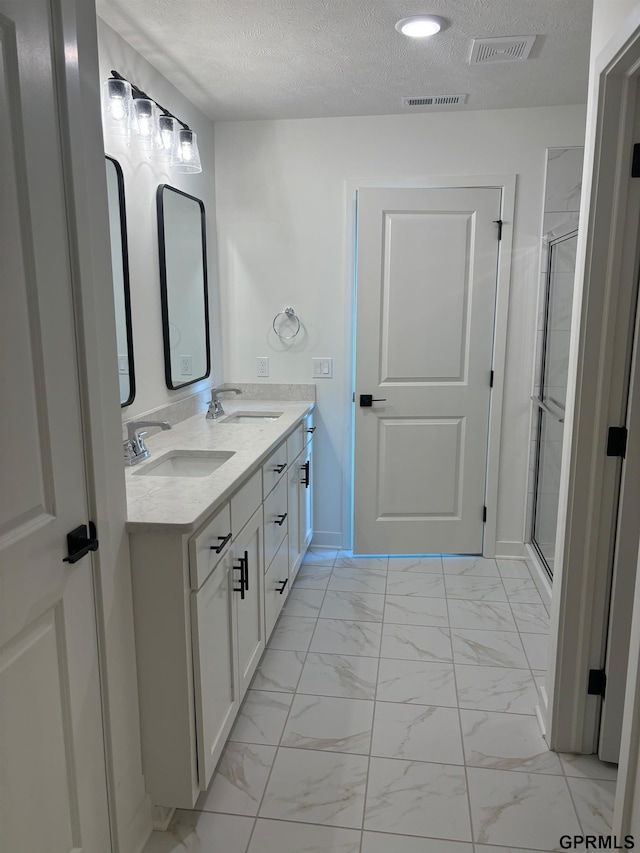 bathroom featuring vanity, an enclosed shower, and a textured ceiling