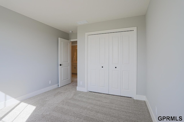 unfurnished bedroom featuring light carpet and a closet