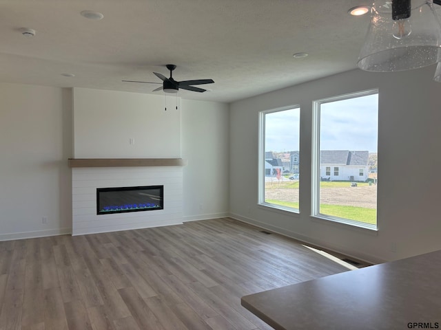 unfurnished living room with ceiling fan and light hardwood / wood-style flooring