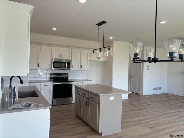 kitchen with white cabinets, a kitchen island, sink, and appliances with stainless steel finishes