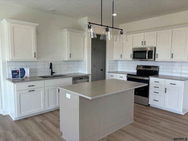 kitchen featuring a center island, sink, hanging light fixtures, white cabinets, and appliances with stainless steel finishes