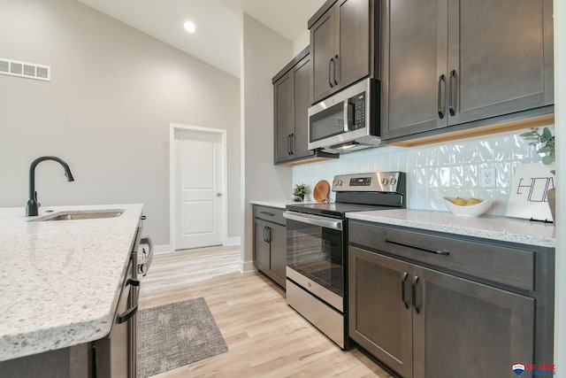 kitchen featuring decorative backsplash, dark brown cabinets, stainless steel appliances, sink, and light hardwood / wood-style floors