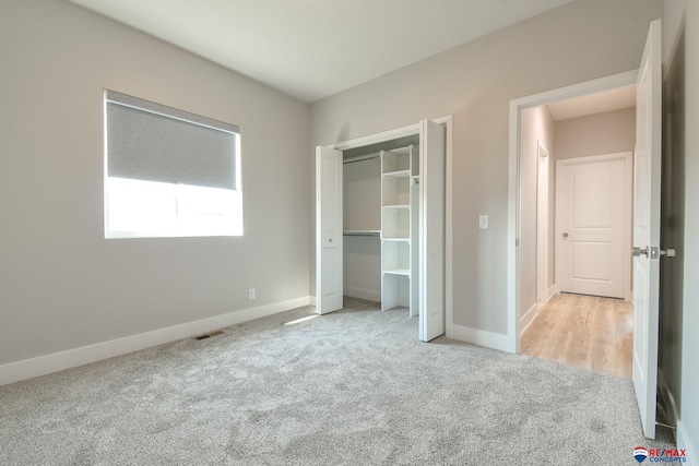 unfurnished bedroom featuring light carpet and a closet