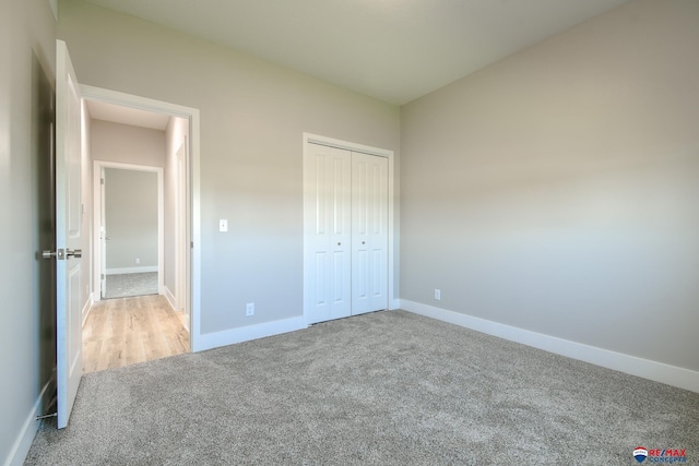 unfurnished bedroom with light colored carpet and a closet