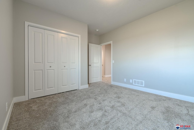 unfurnished bedroom with light carpet and a closet