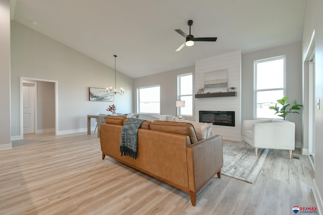 living room with a fireplace, ceiling fan with notable chandelier, high vaulted ceiling, and light hardwood / wood-style flooring