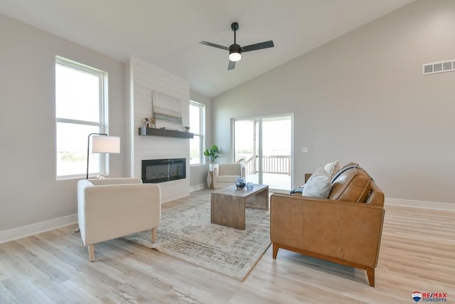 living room with a fireplace, light hardwood / wood-style floors, ceiling fan, and lofted ceiling