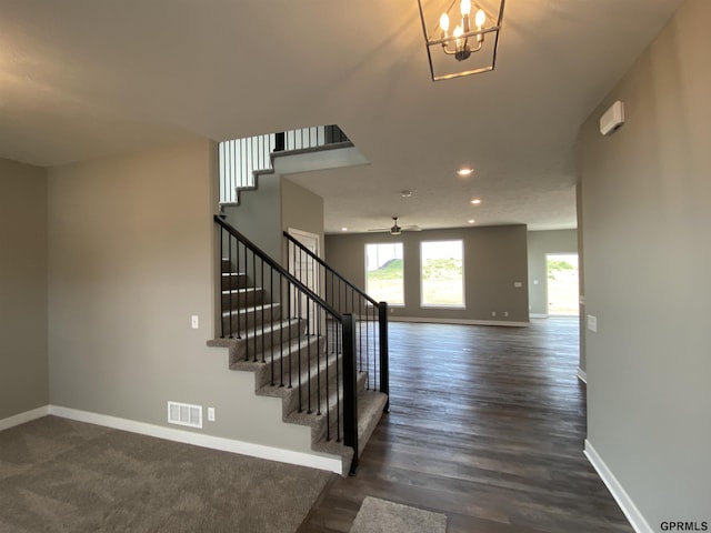 stairs with wood-type flooring and ceiling fan with notable chandelier