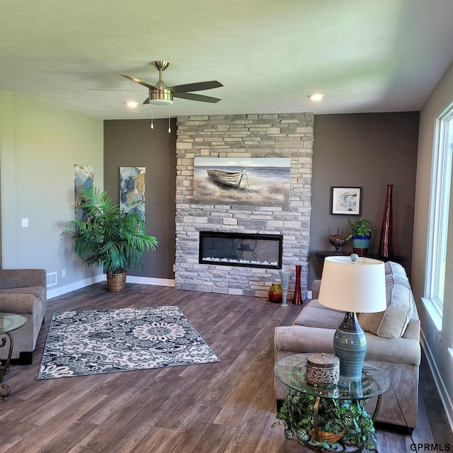 living room featuring a stone fireplace, plenty of natural light, and dark hardwood / wood-style floors