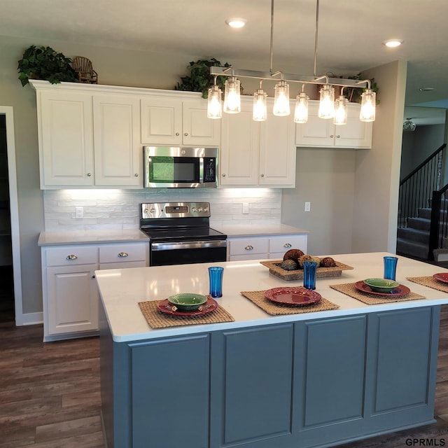 kitchen with stainless steel appliances, dark wood-type flooring, pendant lighting, white cabinets, and a center island