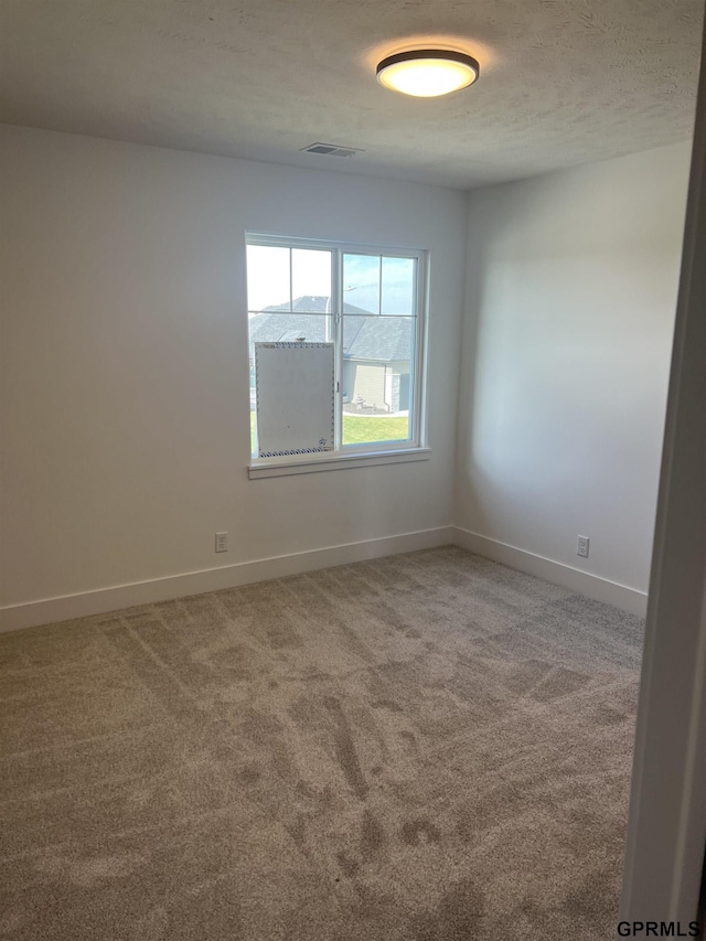 spare room featuring carpet and a textured ceiling