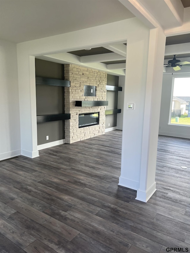 unfurnished living room with a fireplace, built in features, ceiling fan, and dark wood-type flooring