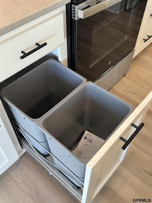 room details with white cabinets and hardwood / wood-style floors