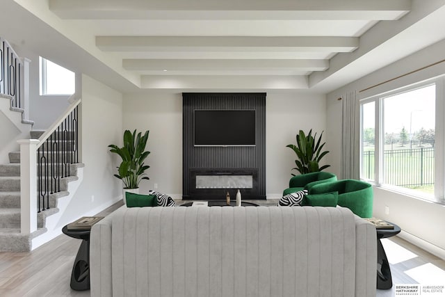 living room featuring beam ceiling, radiator, a fireplace, and light hardwood / wood-style flooring