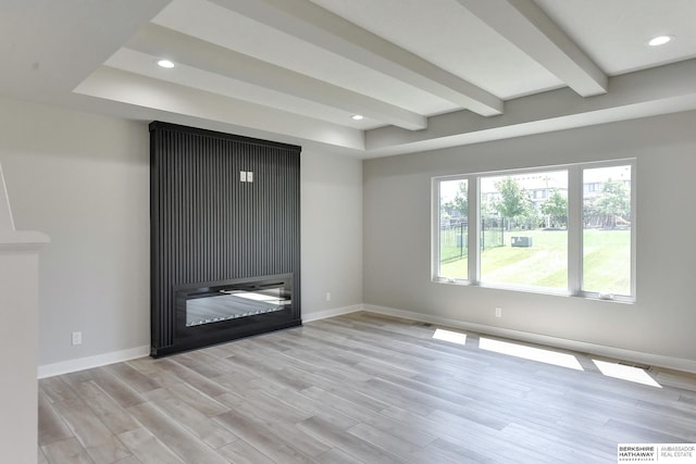 empty room featuring beamed ceiling and light wood-type flooring