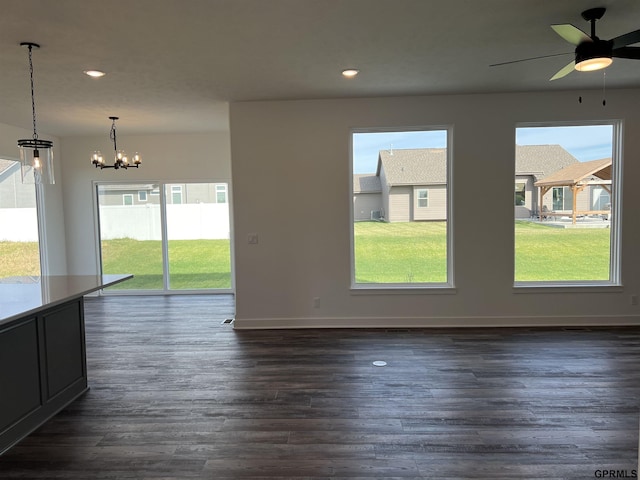 unfurnished room featuring ceiling fan with notable chandelier and dark wood-type flooring