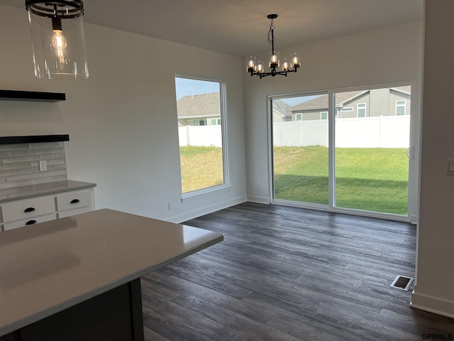 unfurnished dining area featuring a notable chandelier and dark wood-type flooring