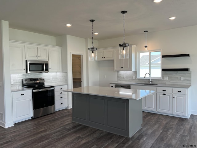 kitchen featuring white cabinetry, a center island, sink, pendant lighting, and appliances with stainless steel finishes