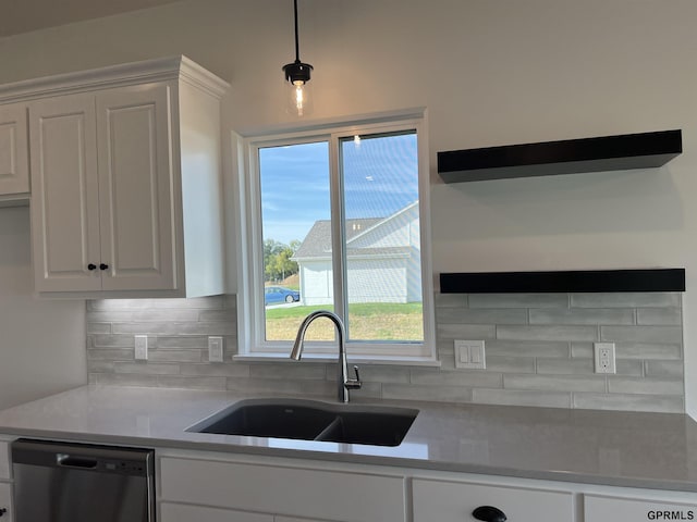 kitchen featuring decorative backsplash, stainless steel dishwasher, sink, white cabinetry, and hanging light fixtures