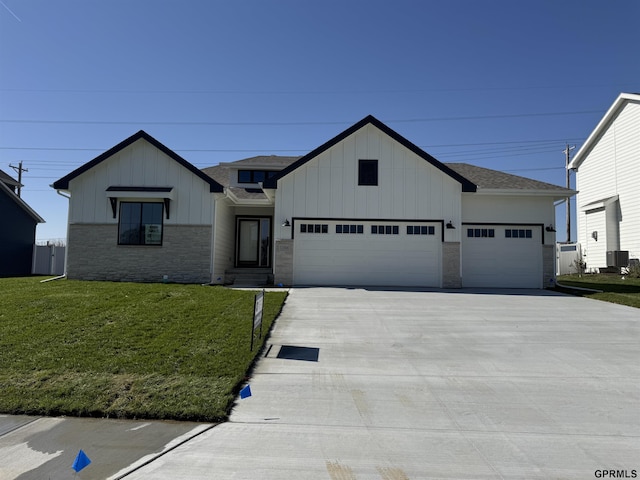 view of front of property featuring a garage, concrete driveway, board and batten siding, and a front yard