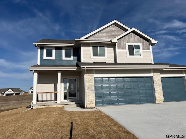 view of front of house with a front yard, an attached garage, covered porch, concrete driveway, and board and batten siding