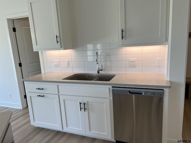 kitchen featuring stainless steel dishwasher, white cabinets, backsplash, and a sink