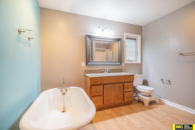 bathroom with hardwood / wood-style floors, vanity, toilet, and a bathing tub