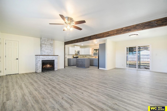 unfurnished living room featuring a tile fireplace, ceiling fan, light hardwood / wood-style flooring, and beamed ceiling